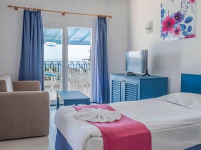Gemütliches Hotelzimmer mit Bett, Sofa, TV und Balkontür mit Blick auf Terrasse