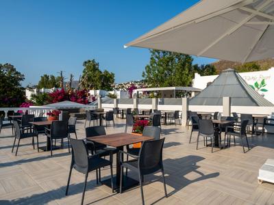 Nowoczesny taras hotelowy z stolikami, krzesłami i parasolami pod czystym niebieskim niebem.