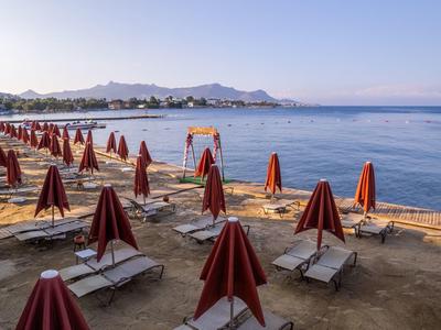 Lettini vuoti con ombrelloni rossi chiusi sulla spiaggia tranquilla in condizioni di bel tempo.