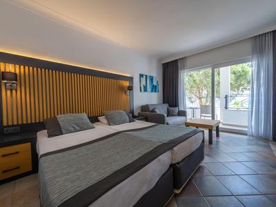 Helles Hotelzimmer mit Doppelbett, Sitzbereich und großem Fenster mit Blick nach draußen.