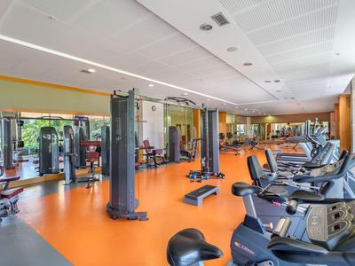 Innenansicht eines modernen Fitnessraums im Hotel mit verschiedenen Trainingsgeräten und orangem Boden.
