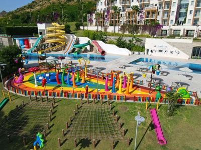 Bunter Wasserspielplatz mit Rutschen und Pools in einem Hotelresort mit umliegenden Gebäuden.
