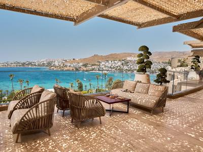 Terrasse mit gemütlichen Rattanmöbeln und Blick auf das Meer und eine Küstenstadt.