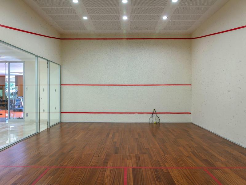 Pusta hala do squasha z drewnianą podłogą i białymi ścianami z czerwonymi liniami.
