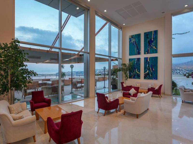 Nowoczesny hotelowy salon z dużymi szklanymi oknami i widokiem na miasto.