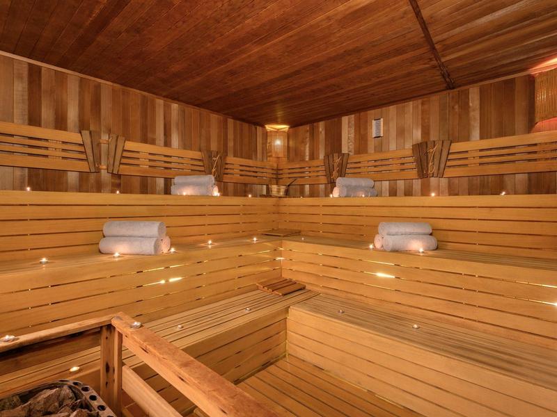 Wnętrze drewnianej sauny z wieloma rzędami siedzeń i ciepłym oświetleniem.