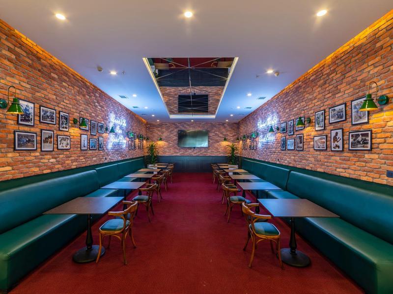 Przytulna część wypoczynkowa z czerwonym dywanem, zielonymi kanapami i zdjęciami na ceglanej ścianie.