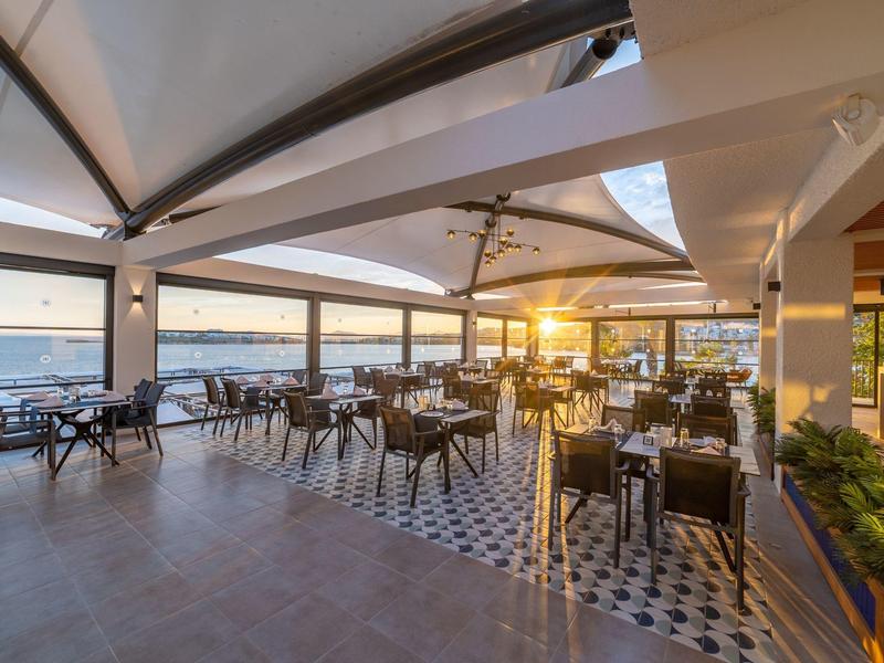 Taras z krzesłami i stołami z widokiem na morze i zachód słońca.