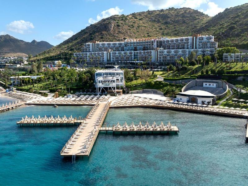 Luksusowy hotel z wieloma basenami na wybrzeżu, otoczony górami i czystą wodą.