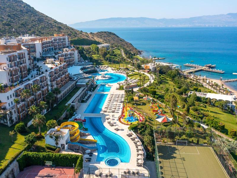 Luksusowy hotel z wieloma basenami, leżakami i widokiem na morze w nadmorskim krajobrazie.