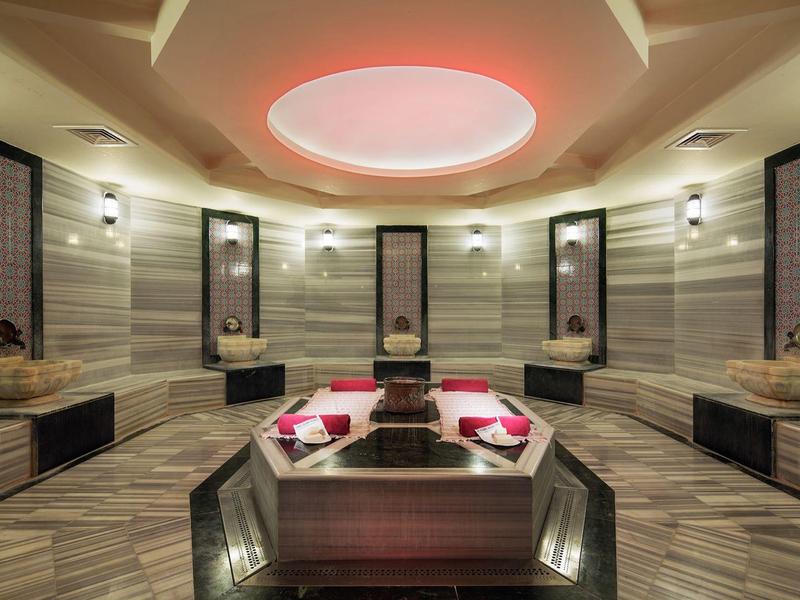 Luxe spa ruimte met marmeren design, centrale zitplaatsen en zachte sfeerverlichting.