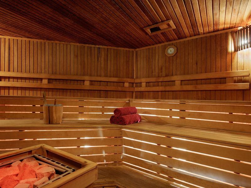 Gezellige houten sauna met bankjes en warme verlichting.