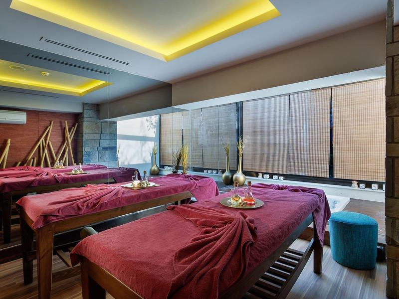 Spa kamer met massagetafels bedekt met rode handdoeken en zacht warm licht.