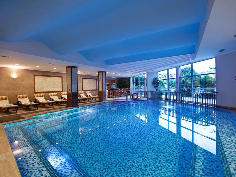Overdekt zwembad met blauwe verlichting en ligstoelen in een hotel.