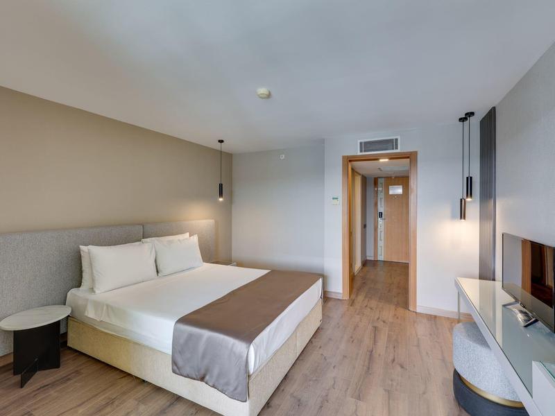 Modern hotelkamer met tweepersoonsbed, houten vloer, nachtkastjes en tv.