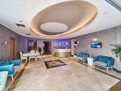 Helles Hotellobby mit eleganter Rezeption, blauer Bestuhlung und modernem Deckendesign.