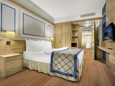 Modernes Hotelzimmer mit großem Bett, Holzverkleidung und Flachbildfernseher.