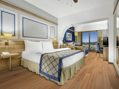 Hotelzimmer mit großem Bett, Holzfußboden und Aussicht auf das Meer.