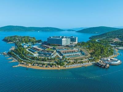 Vista aérea de un complejo hotelero en una pequeña isla rodeada de mar azul.
