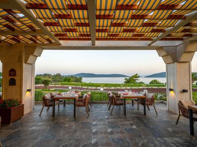 Überdachte Terrasse mit Holzmöbeln und Blick auf Garten und Wasser.