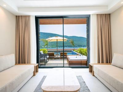 Moderner Hotelzimmer mit Blick auf Terrasse, Pool und Berge im Hintergrund.
