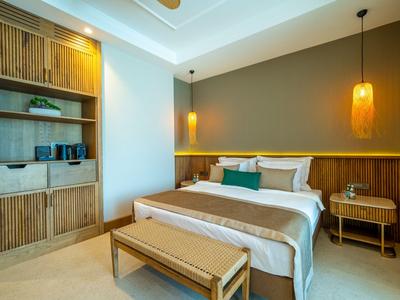 Modern eingerichtetes Hotelzimmer mit großem Bett, Holzmöbeln und warmem Licht.