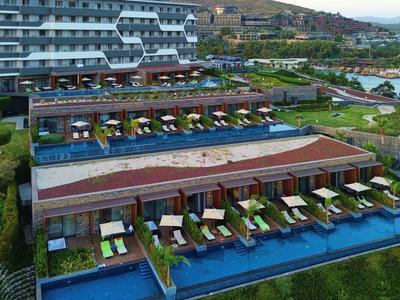 Luxuriöses Hotel mit privaten Pools, Liegestühlen und Meerblick in einer grünen Umgebung.