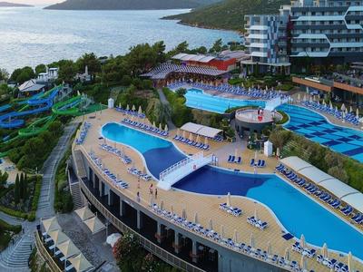 Luxuriöses Hotelresort mit mehreren Pools, Liegestühlen und Meerblick an der Küste.
