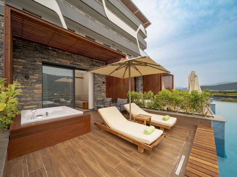 Terraza con dos tumbonas, sombrilla y piscina privada en un hotel moderno.