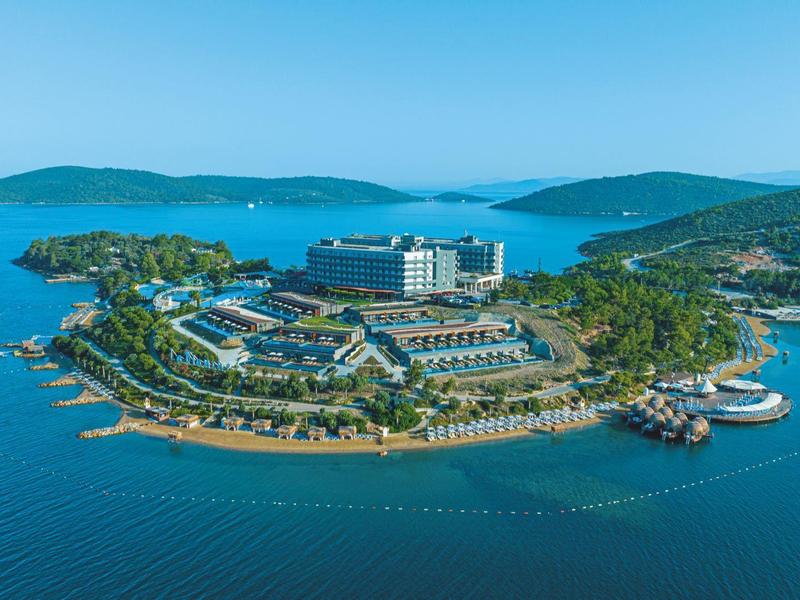 Vista aérea de un complejo hotelero en una pequeña isla rodeada de mar azul.