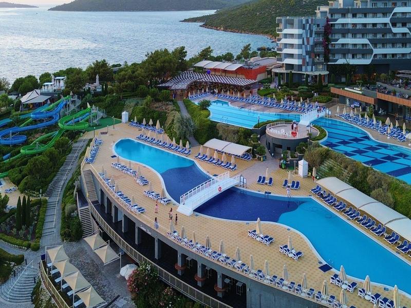 Piscina al aire libre y tumbonas en un hotel moderno con vista al mar.