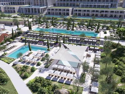 Groot hotelzwembad met ligstoelen, parasols en aangelegde tuinen in een moderne omgeving.