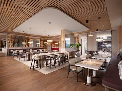 Moderne Hotel-Lounge mit Holzdecke, gedeckten Tischen und gemütlichen Sitzgelegenheiten.