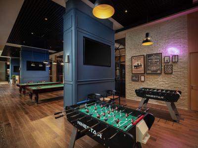 Moderner Spielbereich mit Kicker, Tischtennis und Billardtischen in einem Hotel.