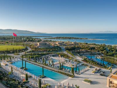 Blick auf ein Resort mit Pool und Meer im Hintergrund, unter klarem Himmel.