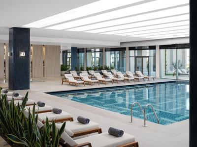 Helles Hallenbad mit Liegestühlen und modernen Dekorationselementen in einem Hotel.