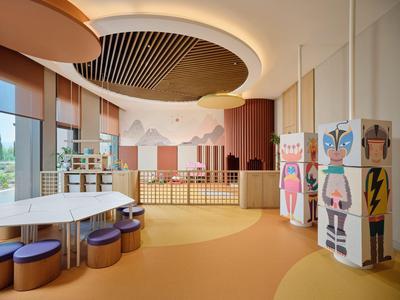 Moderner, heller Hotel-Spielbereich mit bunten Sitzkissen und dekorativen Maltischen.