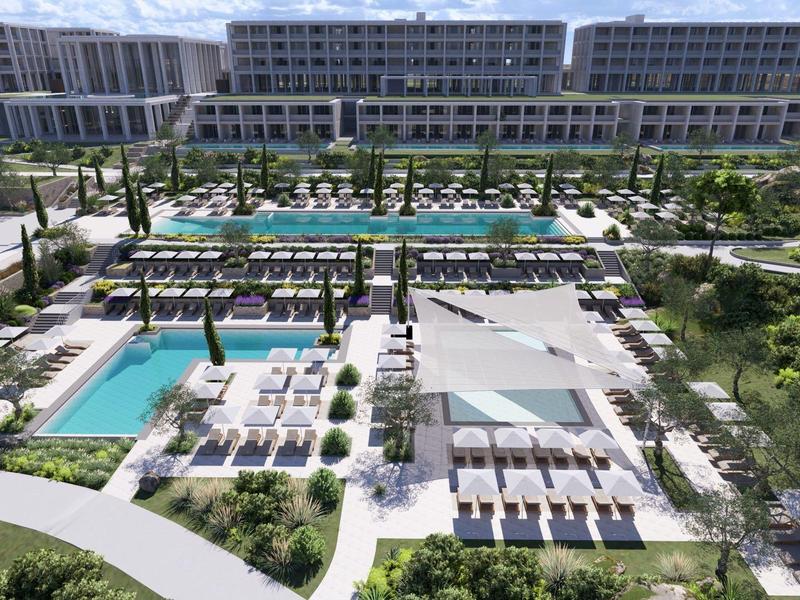 Modern resort met meerdere zwembaden, ligstoelen en groene tuinen onder een heldere hemel.