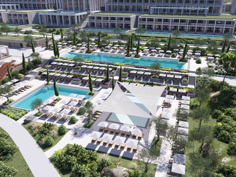 Groot hotelzwembad met ligstoelen, parasols en aangelegde tuinen in een moderne omgeving.