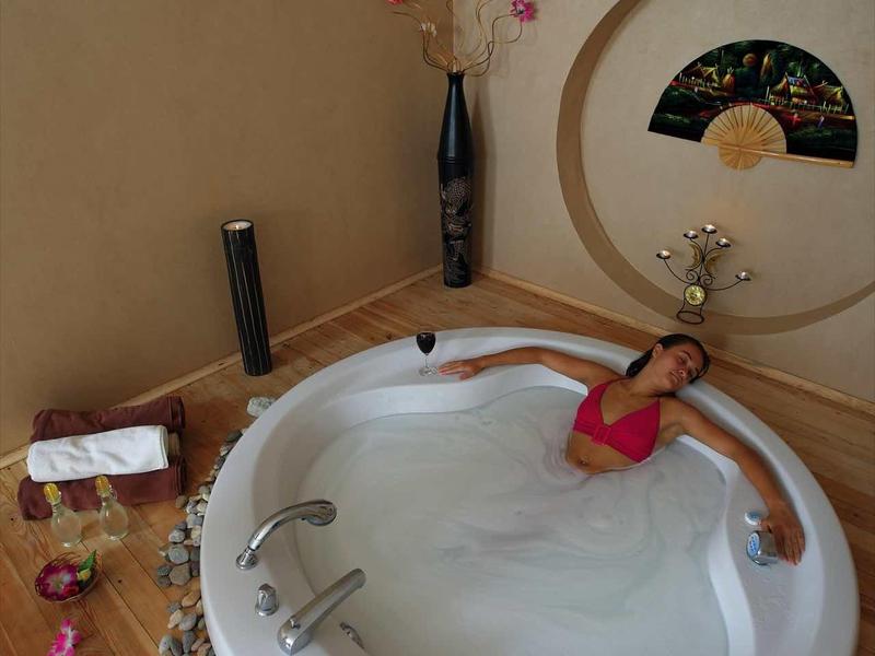 Round jacuzzi in a spa area with wooden floor and decorative stones