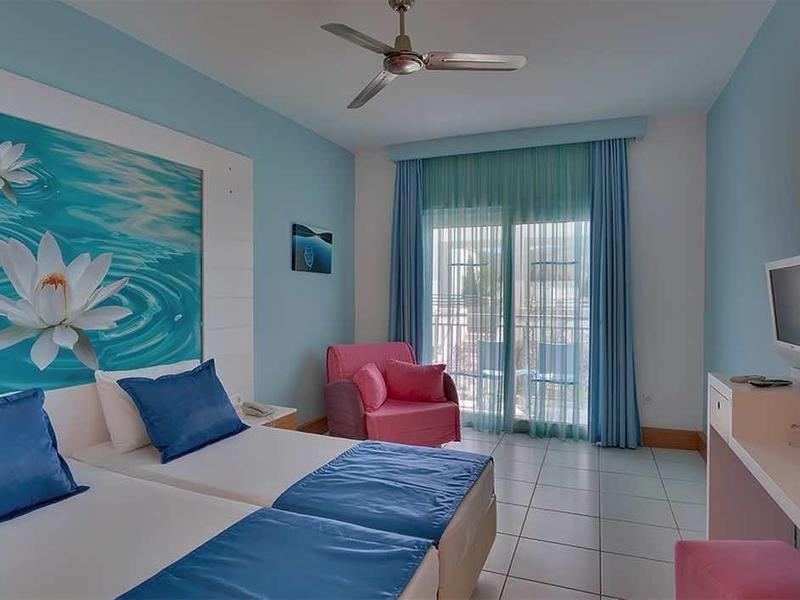 Modern hotel room with double bed, blue-white color scheme, and large floral artwork.