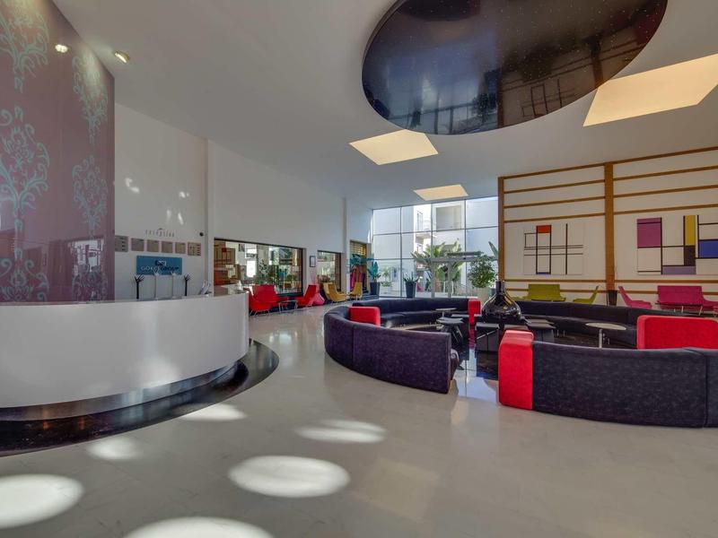 Modern hotel lounge with abstract wall art, comfortable seating, and large windows.