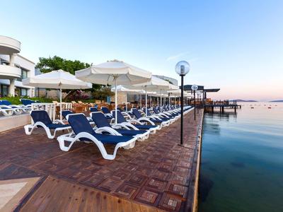 Empty lounge chairs and umbrellas on a wooden pier by the calm sea.