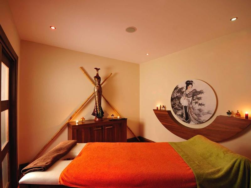 Cozy hotel room with double bed, colorful blankets, and ambient lighting.