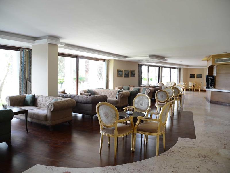 Spacious hotel lounge with sofas and round tables on wood and marble flooring