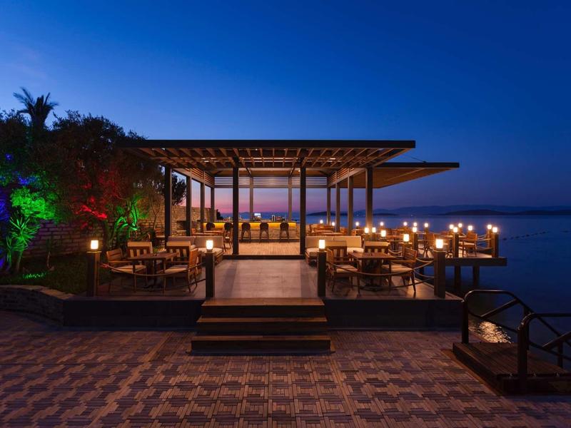 Evening beach bar with stylish lighting and a view of the calm sea.