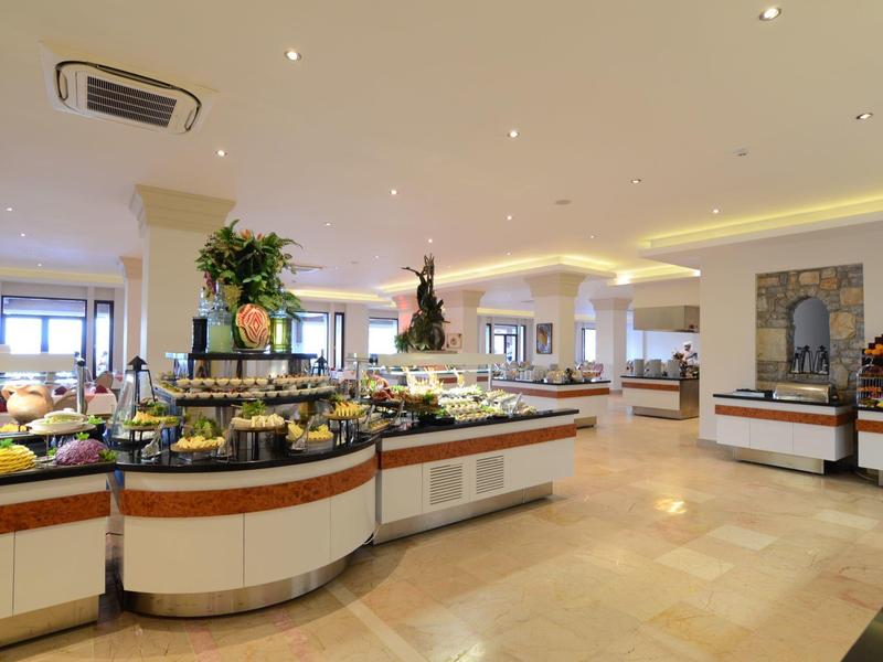 Großer Buffetbereich mit vielfältigen Speisen auf weißen Theken in hellem, modernem Raum.