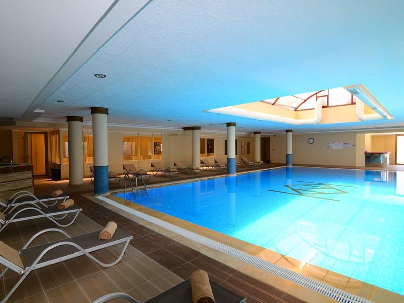 Helles Hallenbad mit bequemen Liegestühlen und großem Oberlicht für Tageslicht.