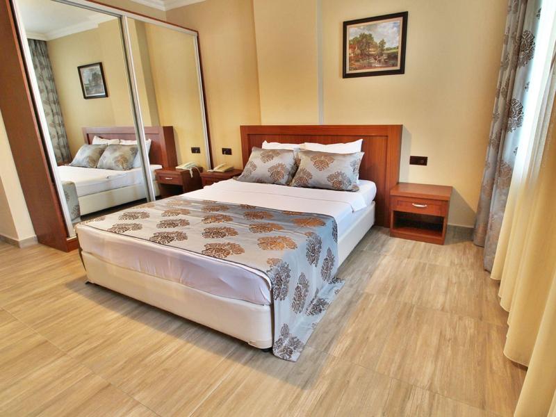 Schlafzimmer mit Doppelbett, Holzboden, Nachttischen, großem Spiegel und einem Bild an der Wand.