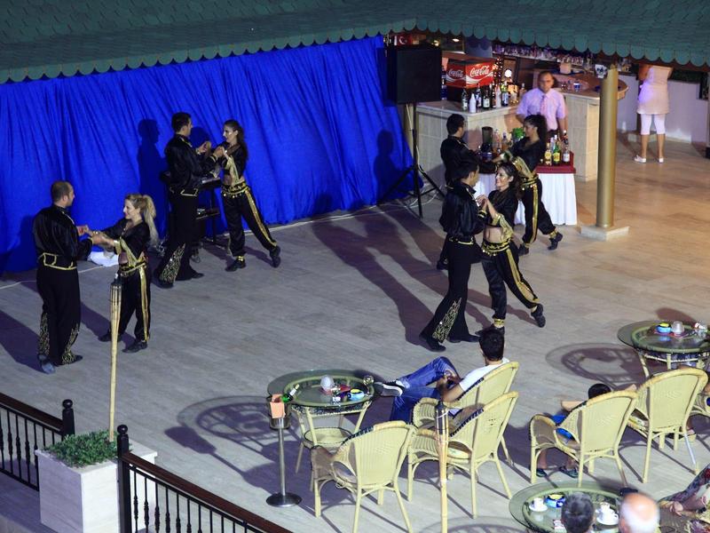 Menschen in schwarzen Uniformen üben Kampfsport auf hellgraßem Boden vor blauer Wand.